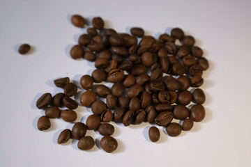 Roasted brown coffee beans, isolated on a white background, form a heap, ready for a rich, dark espresso drink