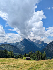 Obraz premium Mountain landscape in the Berchtesgaden National Park. View from the Eibl Chapel across a green meadow with a small, traditional wooden house over to Maria Kirchental at the foot of the Loferer Steinb
