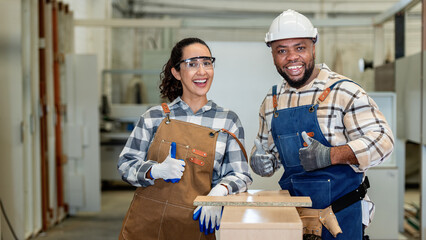 Two people in a workshop, one of them is wearing a hard hat