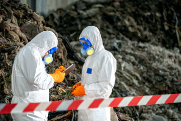 Two scientists in full protective hazmat suits working outdoors with laboratory tools near rocky terrain and caution tape, conducting environmental or hazardous material testing © BESTIMAGE