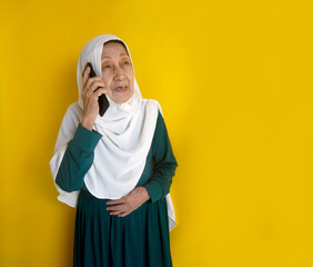 Senior Asian Woman Talk on The Phone, Standing Against Yellow Background. Studio Shot