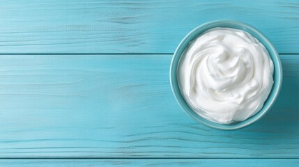 Whipped cream in bowl on light blue wooden table