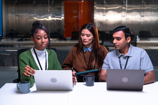 Programmer and developer team collaborates in office setting using laptops and code to solve problems while discussing ideas and working efficiently on project together