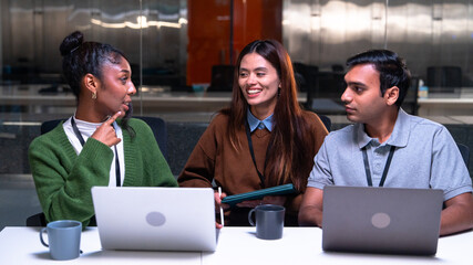 Programmer team in office discussing code and development ideas with laptops and notebooks while...