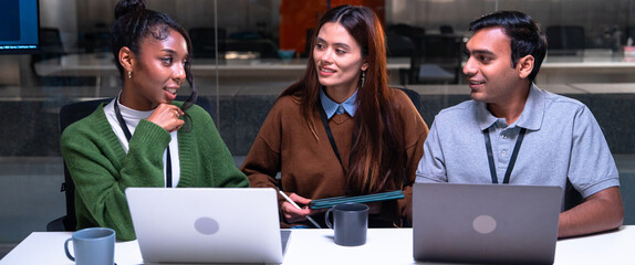 Programmer and developer collaborate in office environment discussing code on laptops while sharing ideas and working on project with focus and teamwork