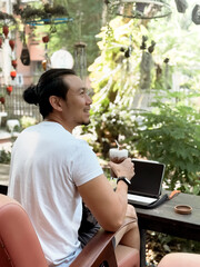 Happy smile man drink iced cocoa while working online with his tablet computer in the cafe.