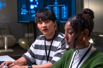 Two programmer developers collaborate in office environment discussing code on computer screen while focusing on software development tasks with concentration and teamwork