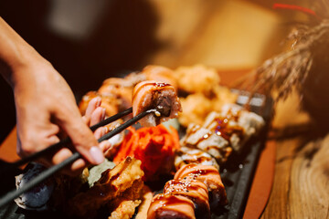 Diner enjoys delicious sushi rolls with chopsticks at a cozy restaurant during evening hours
