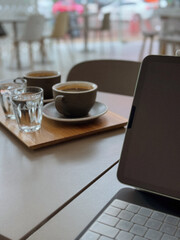 Coffee set with espresso and laptop in modern cafe