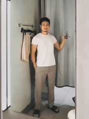 Asian man posing in fitting room with hand in pocket and casual expression