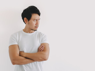 Asian man looking to side with arms crossed and neutral face in white shirt and clean background