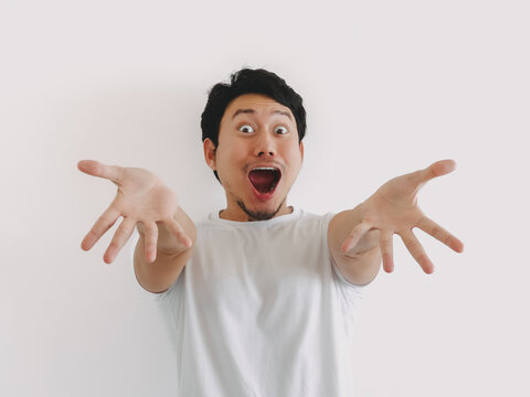 Asian man gesturing with both hands and surprised facial expression in white shirt and clean background