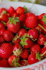 Fresh sweet strawberries in a white bowl on a white background. Seasonal berries.