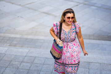 Beautiful middle aged woman walking up stairs against background of concrete square in city on...
