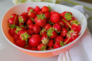 Fresh sweet strawberries in a white bowl on a white background. Seasonal berries.
