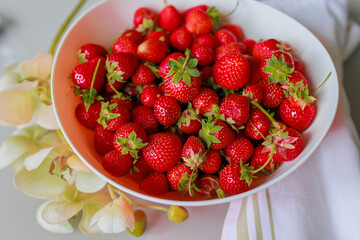 Fresh sweet strawberries in a white bowl on a white background. Seasonal berries.