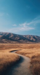 Golden path winds through a dry, mountainous landscape under a vast, blue sky