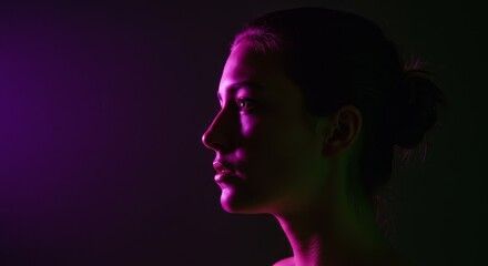 Profile of young woman with colored lighting in dark environment  