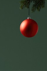 Shiny red ornament hanging from evergreen branch, minimalist hol