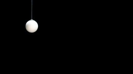 A single white spherical pendant light hangs against a black background, creating a minimalist and modern aesthetic.
