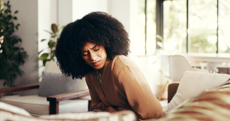 Woman, stomach and cramps or pain on sofa for menstruation, ovarian cysts and discomfort in lounge....