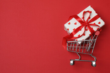 wheelbarrow with gift boxes on red background