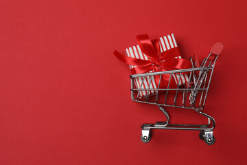 wheelbarrow with gift boxes on red background