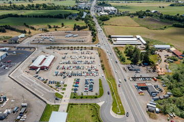 Aerial drone top-down view of a busy and full parking lot at a large dairy factory in Tillamook, Oregon, with many parked cars and highway 101 visible	
