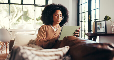 Headphones, woman or relax with tablet in home for streaming movie, online series or watching video. Cozy, african person and digital app on sofa for listening to playlist, audiobook or weekend break