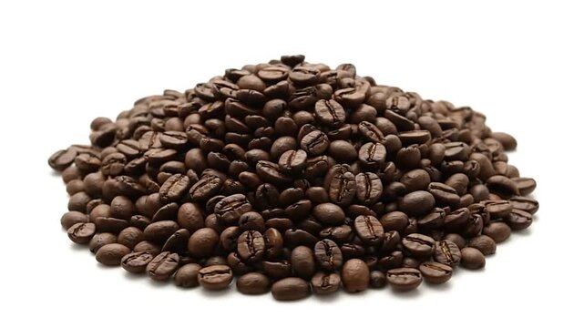 A pile of dark brown roasted coffee beans on a white surface showing their ridges and textures