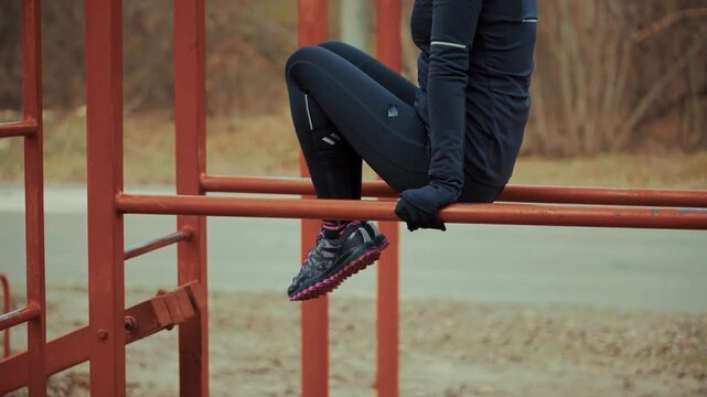 Woman performs core exercise on outdoor parallel workout bars