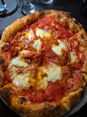 Evocative close-up image of a pizza with tomato, mozzarella, spicy salami and chili pepper
