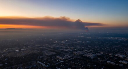 Fototapeta premium Aerial view of urban sprawl with wildfire smoke over the horizon during sunset showing the impact