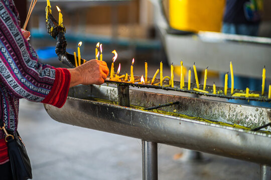asian elderly woman pay homage Light candles at the candlestick to worship the Thai Buddha. in temple thailand belief in Buddhism