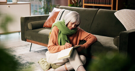 Mature woman, writing and sofa with book for story, novel or author with chapter in home. Female...