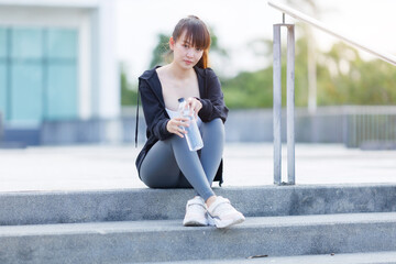 Portrait of beautiful asian Young woman in Black robe sportswear and drinks water working out...