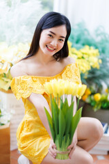Portrait of beautiful happy Smiling asian woman relaxing sitting in yellow dress at cafe interior...
