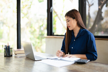 Businesswoman working remotely in a Home office taking notes in a notepad . woman hand writing in...