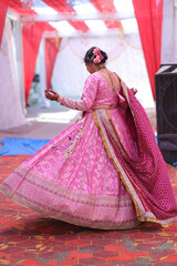 Naklejka premium Indian Woman in Traditional Pink Lehenga and Dupatta at Wedding Venue
