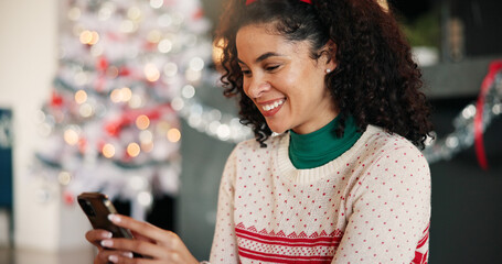 Christmas, woman and typing with phone in home for holiday text, season greeting and chat. Happy,...