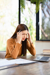 Stressed business woman working on laptop looking worried, tired and overwhelmed. asian female...