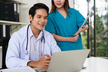 Doctor and nurse discussing over a medical report in hospital. Asian doctor and nurse checking...