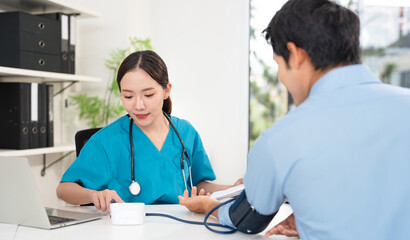 Female doctor in scrub uniform measure blood pressure with electronic monitor in hospital. Caring...