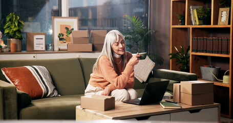 Reading, laptop and coffee with old woman on sofa for retirement policy, planning and review....