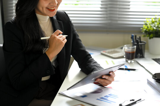 Business executive using digital tablet and reviewing financial reports at desk