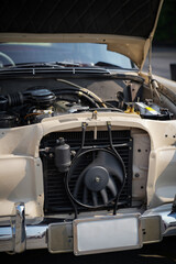 The engine and battery compartment of a classic car, with its detailed mechanical and electrical components, the vintage engineering powering the vehicle.