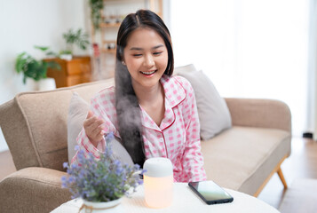 Modern air humidifier during relax or rest, happy asian young woman, girl enjoying aromatherapy...