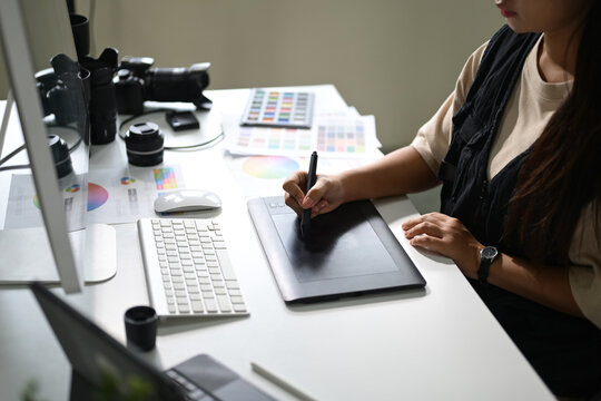Photographer retouching images on a graphic tablet at a workstation