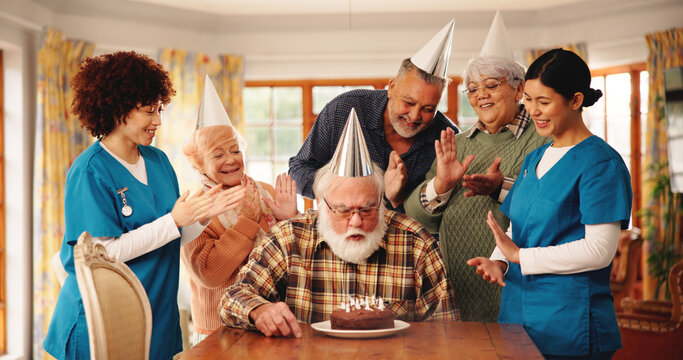 Old people, nursing home and blow birthday cake with clapping, group celebration or happy. Candles, retirement party and senior friends at special event for congratulations with medical caregiver