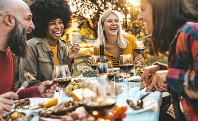Happy friends having bbq dinner party in garden restaurant - Multiracial young people eating grill...